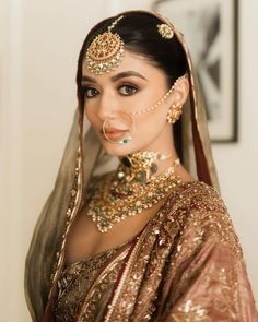 a woman in a bridal outfit with jewelry on her head and nose ring, posing for the camera