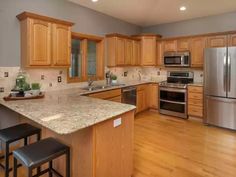 a large kitchen with stainless steel appliances and wooden cabinets, along with hardwood floorsing