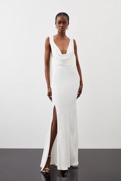 a woman wearing a white dress with a slit in the side and one leg up