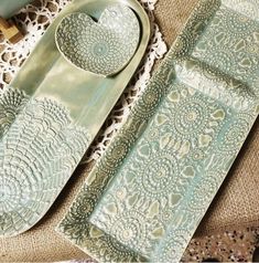 an assortment of green and white dishes on a lace doily with scissors, spoons and other items