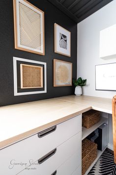 a white desk with drawers and pictures on the wall