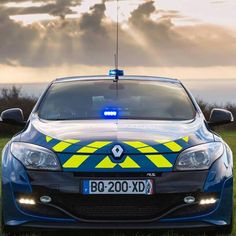 a police car parked in the grass with its lights on and flashing blue, yellow and white