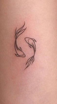 a small tattoo on the side of a woman's thigh, with two fish in it