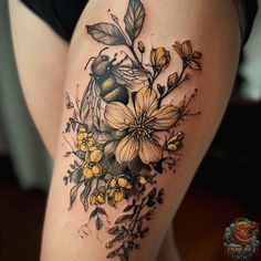 a woman's thigh with flowers and a bee tattoo on her leg, which is black and yellow