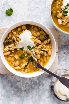 two bowls of soup with beans, sour cream and cilantro on the side