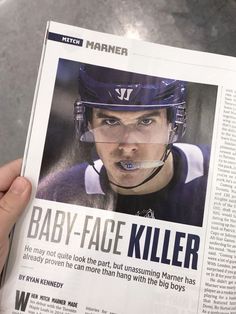 a person holding up a newspaper with an image of a baby face killer on it