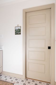 a white door in a room with tile flooring and wall decorations on the walls