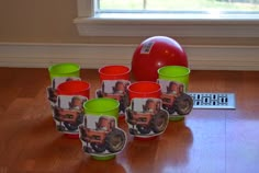 there are many cups with pictures on them next to a red ball and remote control