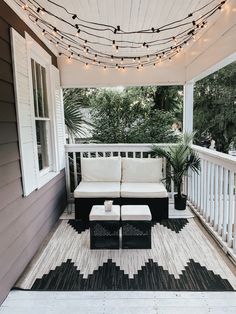 a white couch sitting on top of a wooden porch next to a black and white rug