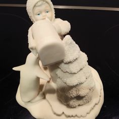 a white figurine holding a baby doll on top of it's back