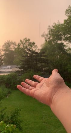 a person's hand is covered with mud as the sun sets