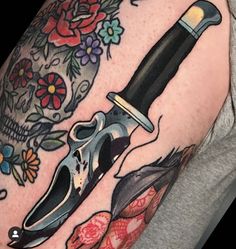 a man with a tattoo on his arm has a knife and skull in the background