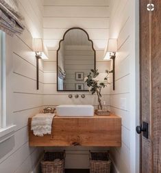 a bathroom with a sink, mirror and two wicker baskets on the floor in front of it