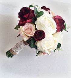 a bridal bouquet with red and white flowers on it's side, against a white background