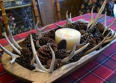 a candle and antlers in a wooden bowl on a table