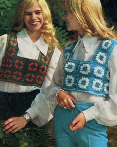 two young women standing next to each other in front of some trees and bushes smiling