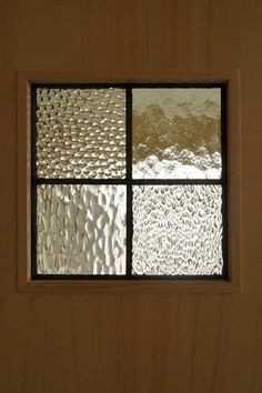 a window with four different shades of glass on the outside and inside, in front of a wooden wall