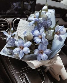 a bouquet of blue flowers sitting on top of a car dashboard next to a steering wheel