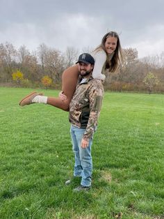 a man carrying a woman on his back while standing in the middle of a field