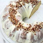 a bundt cake with white frosting and nuts on top