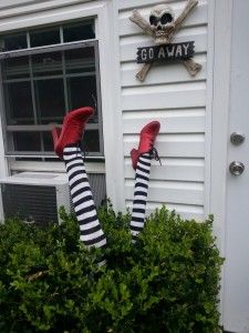 someone wearing striped socks and red shoes standing in front of a house with their feet up