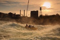 a group of people riding on the back of a yellow raft down a river next to tall buildings