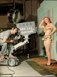 a man standing next to a woman in front of a television camera on the set