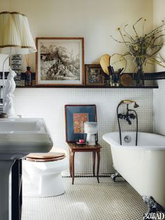 a bathroom with a toilet, sink and bathtub in the corner next to a painting