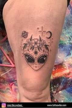 a woman's thigh with an alien face tattoo on her leg and the word c is