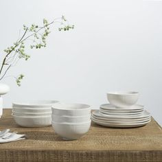 a table topped with white plates and bowls