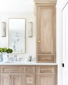 a bathroom with wooden cabinets and marble counter tops in front of a large mirror on the wall