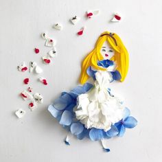 a paper doll with blue and white dress next to red and white hearts on the wall