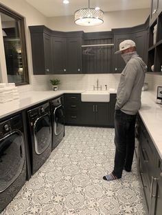 a man standing in a kitchen looking at the washer and dryer