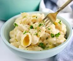 a blue bowl filled with macaroni and cheese on top of a white table