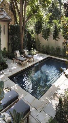 an outdoor swimming pool with lounge chairs and trees in the backround, surrounded by greenery