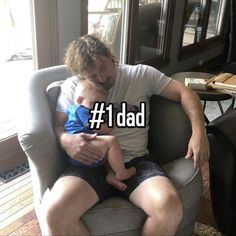 a man sitting in a chair holding a baby with the words 1 dad on it