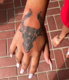 a woman's hand with a bull tattoo on it