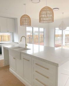 a kitchen with white cabinets and an island countertop in front of two large windows