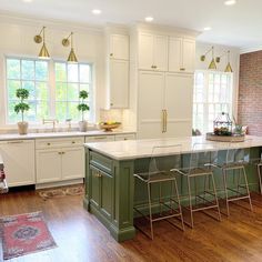 a large kitchen with white cabinets and green island counter tops, along with bar stools