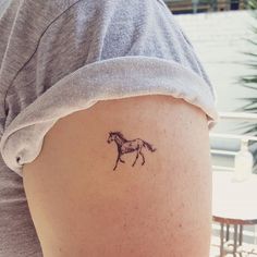 a woman with a small tattoo on her thigh shows a horse running across the ground