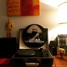 a record player sitting on top of a wooden table next to a lamp and pictures