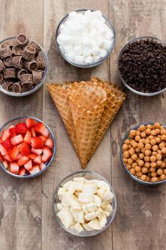 bowls filled with different types of food on top of a wooden table next to chocolate chips and strawberries