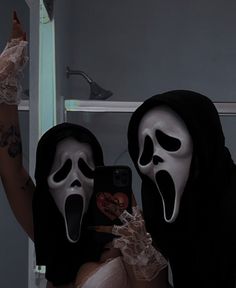 two people in halloween costumes taking a selfie with their cell phone while wearing masks