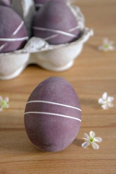 some kind of egg sitting on top of a wooden table next to flowers and eggshells