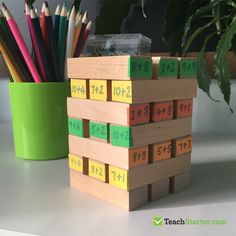 a stack of wooden blocks sitting next to a green cup filled with pencils