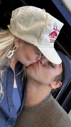 a man and woman kissing each other while wearing hats