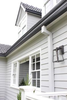 a house with white siding and black shingles on the side of it, next to a planter