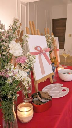 an easel with flowers and candles on a table