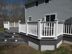 a deck with white railings in front of a house