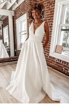 a woman standing in front of a mirror wearing a white wedding dress with pockets on the side